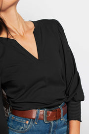 close-up of a black v-neck top with puffed and cuffed 3/4 sleeves