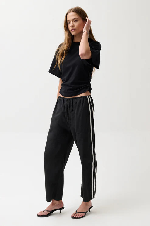 Woman wearing black pants with white stripes.