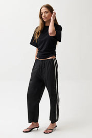 Woman wearing black pants with white stripes.