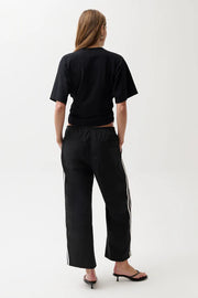 Woman wearing black pants with white stripes.