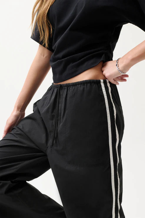 Woman wearing black pants with white stripes.