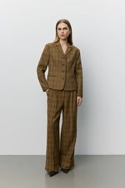 A woman modeling a brown plaid blazer with a double-breasted button closure and notch lapels. 