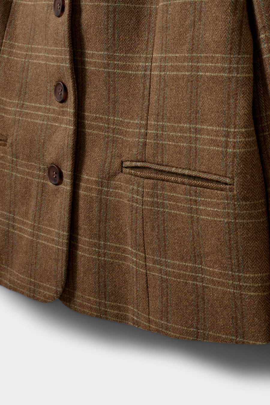 A woman modeling a brown plaid blazer with a double-breasted button closure and notch lapels. 