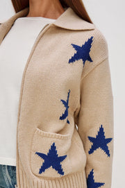 Close-up of a beige zip-up sweater with blue star patterns and front pockets