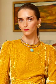 Woman wearing a yellow dress with jewelry in an indoor setting