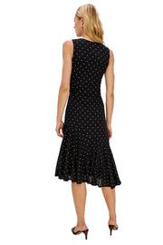 Woman wearing a black sleeveless dress with white polka dots on a white background