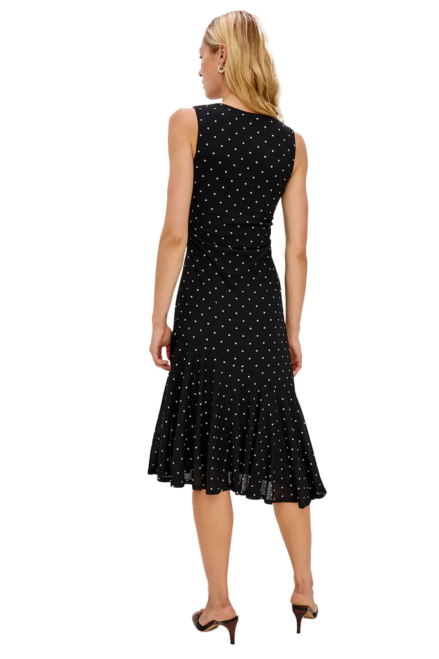 Woman wearing a black sleeveless dress with white polka dots on a white background