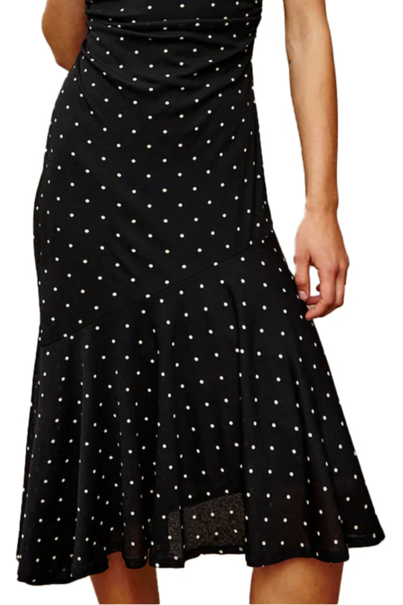 Woman wearing a black dress with white polka dots on a white background