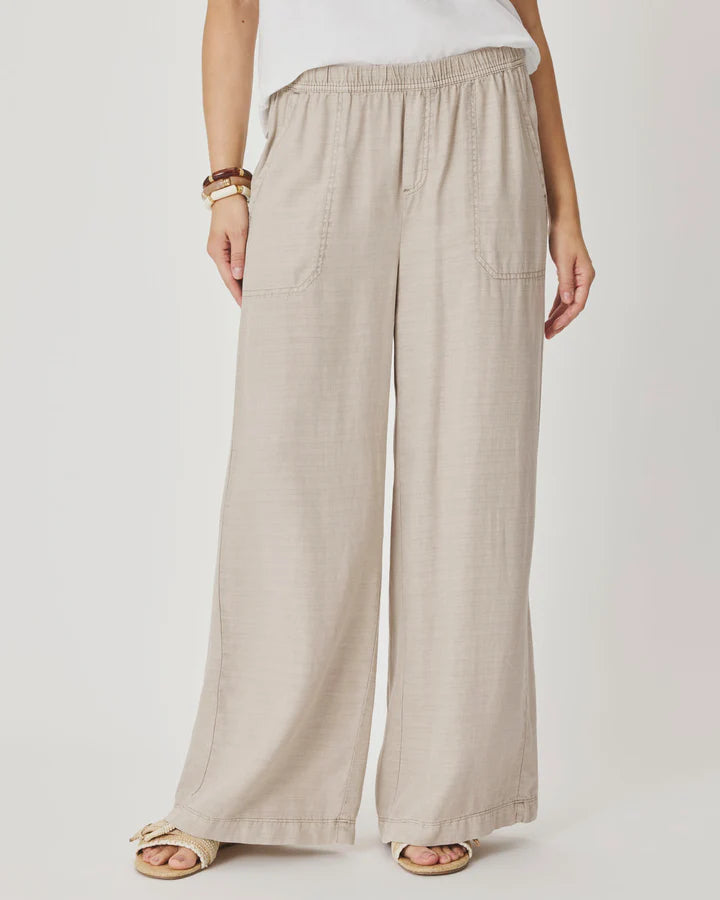 Woman wearing beige wide-leg pants with front pockets. 