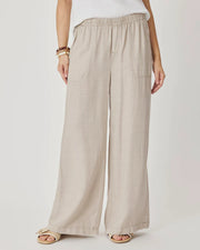 Woman wearing beige wide-leg pants with front pockets. 