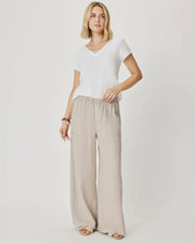 Woman wearing beige wide-leg pants with front pockets. 