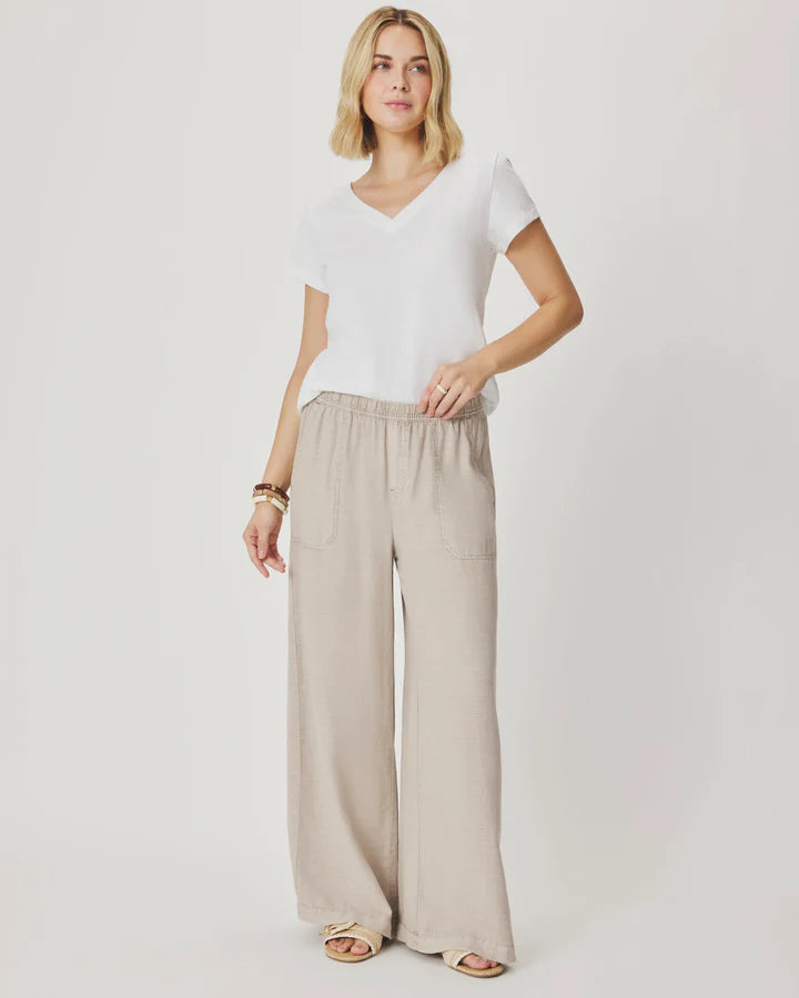 Woman wearing beige wide-leg pants with front pockets. 