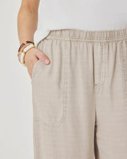 Woman wearing beige wide-leg pants with front pockets. 