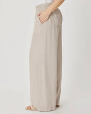 Woman wearing beige wide-leg pants with front pockets. 