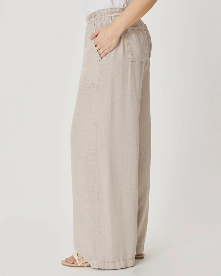 Woman wearing beige wide-leg pants with front pockets. 