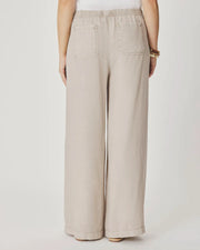Woman wearing beige wide-leg pants with front pockets. 