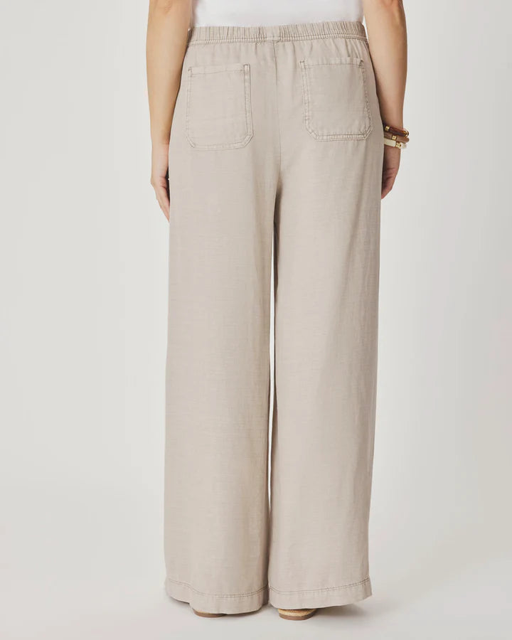 Woman wearing beige wide-leg pants with front pockets. 