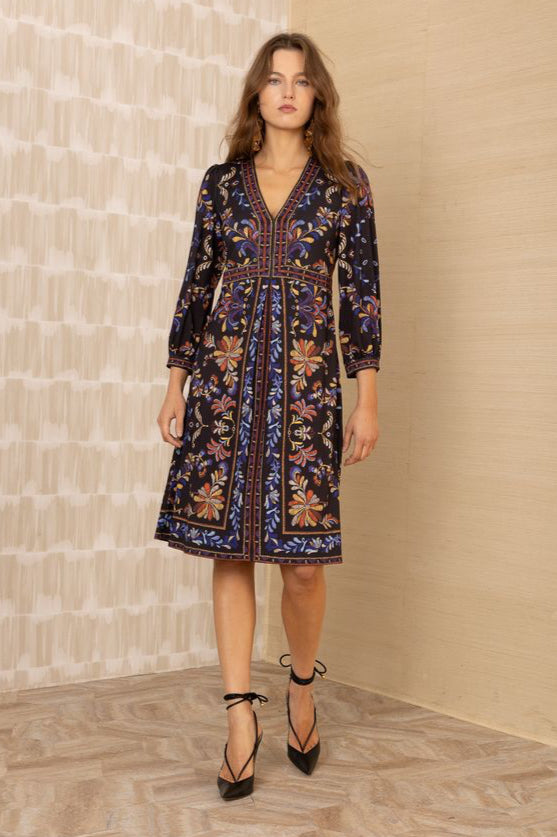 Front view of woman wearing a knee-length black patterned 3/4 sleeve v-neck dress