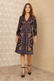 Front view of woman wearing a knee-length black patterned 3/4 sleeve v-neck dress