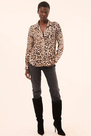 Front full body view of woman wearing a leopard print button down top with gray skinny jeans and tall boots