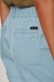 woman wearing light blue high-waisted shorts with front patch pockets and rolled cuffs paired with flat sandals, detail