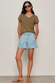 woman wearing light blue high-waisted shorts with front patch pockets and rolled cuffs paired with flat sandals, front