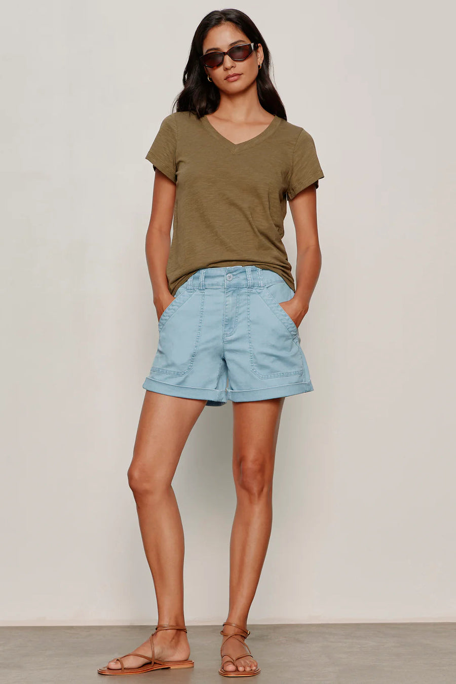 woman wearing light blue high-waisted shorts with front patch pockets and rolled cuffs paired with flat sandals, front