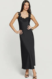Woman wearing a black maxi dress with delicate black lace trim along the neckline and straps