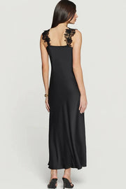 Woman wearing a black maxi dress with delicate black lace trim along the neckline and straps