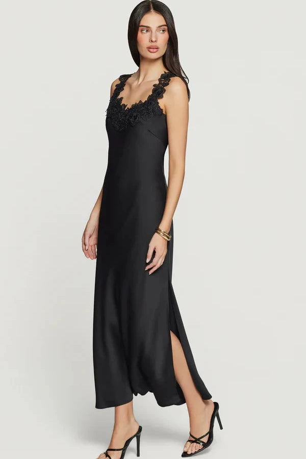 Woman wearing a black maxi dress with delicate black lace trim along the neckline and straps
