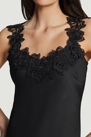 Woman wearing a black maxi dress with delicate black lace trim along the neckline and straps