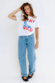 Woman wearing a white t-shirt with a horse and the text 'Stay Wild' graphic and jeans