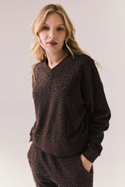 Woman wearing a brown leopard print sweater and pants against a plain background