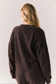 Person wearing a brown leopard print sweater on a plain background