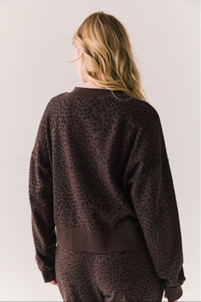 Person wearing a brown leopard print sweater on a plain background