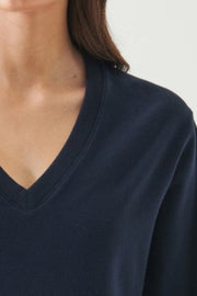 Navy blue long-sleeve shirt worn by a person on a light gray background