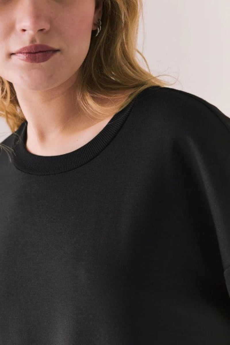 Woman wearing a black top against a plain background