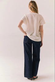 Person wearing a white t-shirt and dark blue jeans on a plain background