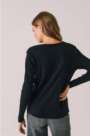 Woman wearing a black long-sleeve shirt with 'Apres Ski Milano Cortina' text 