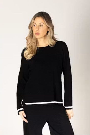 Woman wearing a black outfit with white trim. 