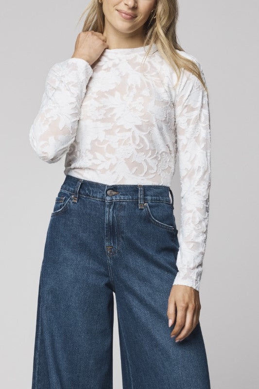 Women wearing white long sleeve top with floral pattern. 