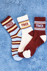 Three pairs of crew socks. One pair is light blue and white with dark red stripes and 'FRENCH' text.