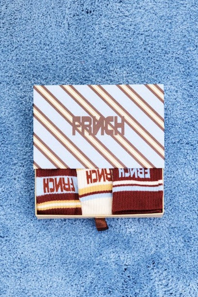 Three pairs of crew socks. One pair is light blue and white with dark red stripes and 'FRENCH' text.