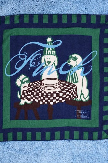 A square vintage scarf featuring a navy blue background with green striped borders, light blue script text reading 'French', and three white poodles sitting around a checkered table. 