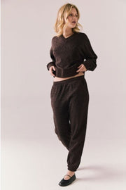 Person wearing a brown leopard print sweater and pant on a plain background