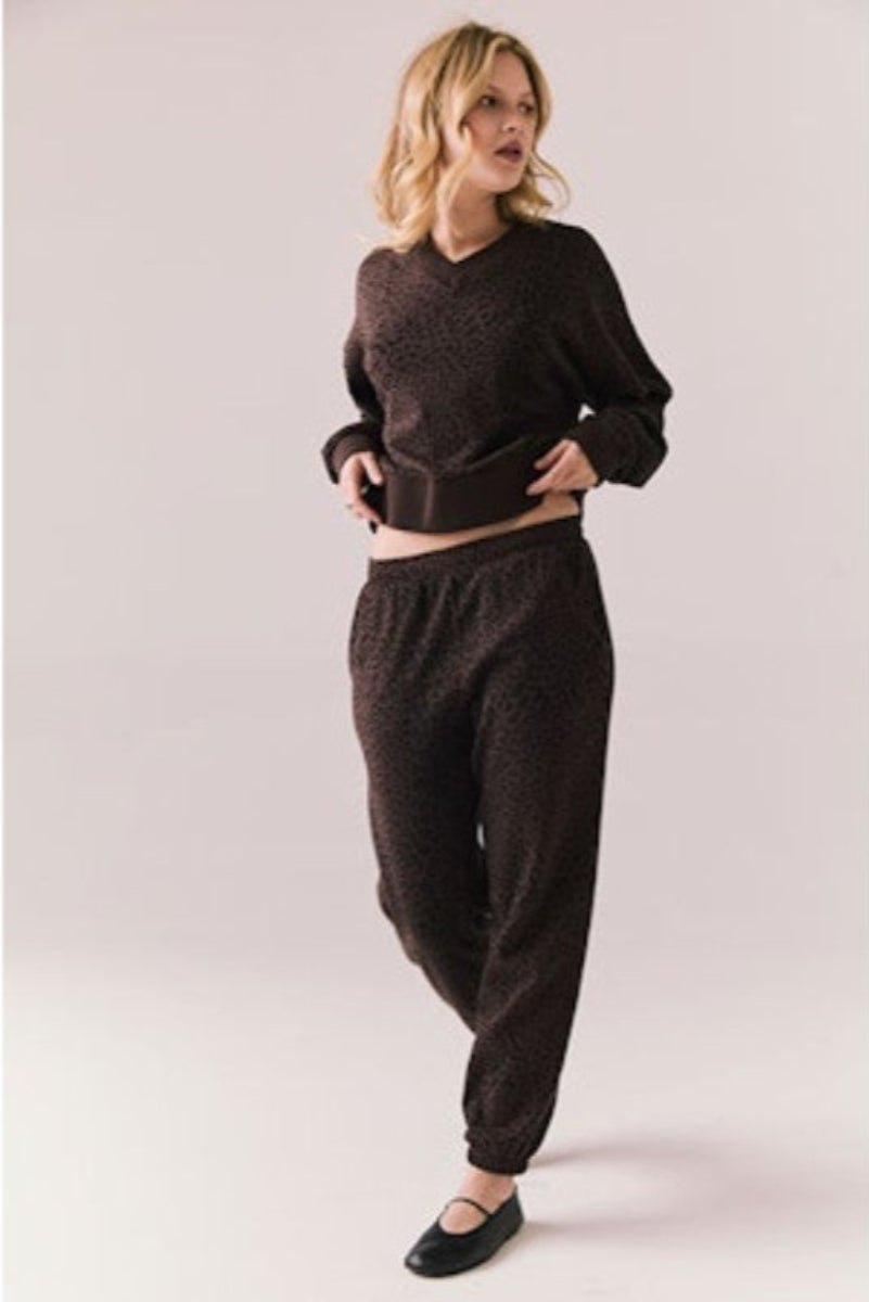 Person wearing a brown leopard print sweater and pant on a plain background