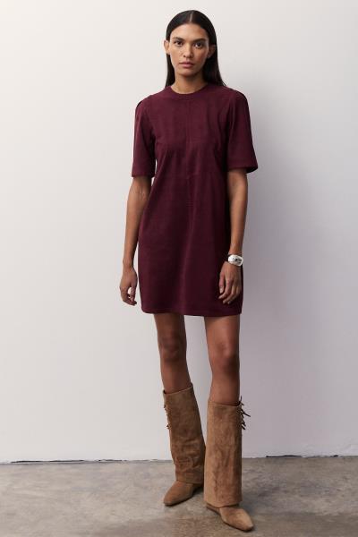 A woman modeling a short-sleeve crewneck mini dress in deep burgundy. 