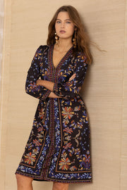 Close-up view of woman wearing a knee-length black patterned 3/4 sleeve v-neck dress