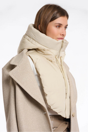 Woman wearing a beige coat with a large scarf on a white background