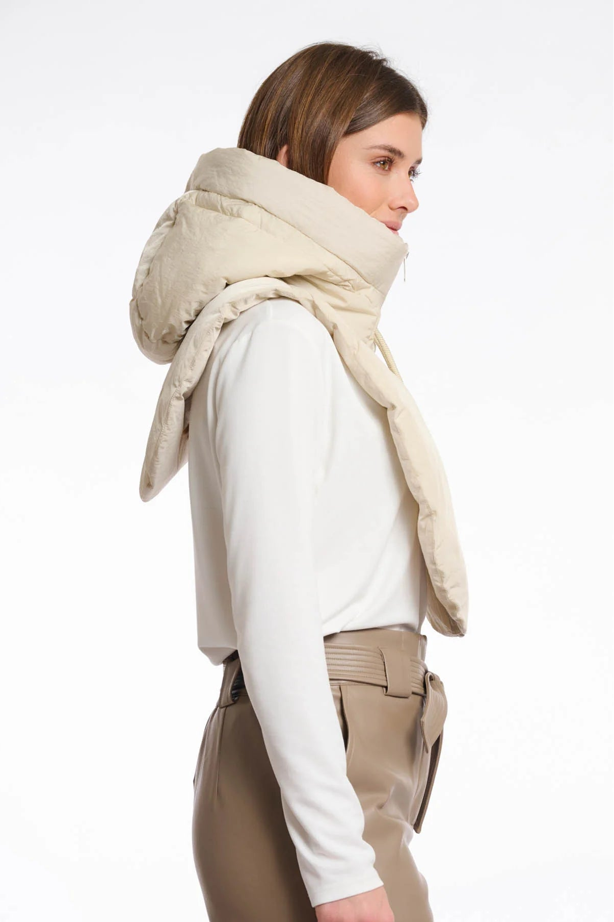 Woman wearing a beige scarf and beige pants on a white background